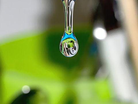 goccia d'acqua macro molto luminosa che riflette l'azzurro dell'acqua, forchette, cucchiai e coltelli