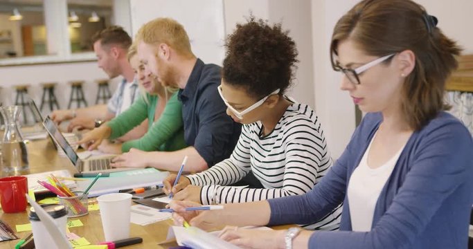 Young creative people posing at table with files and papers concentrated on process of work in modern office.