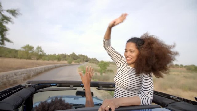 Couple Driving Open Top Car On Country Road 