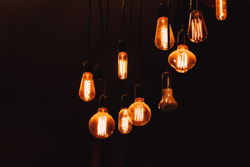 hanging dim vintage style tungsten light bulb on dark background loft style lighting decoration...