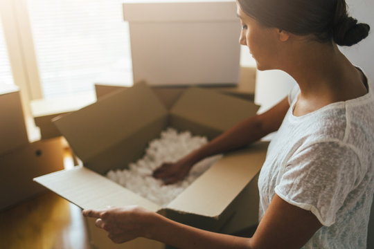 Woman unpacking moving boxes into new apartment