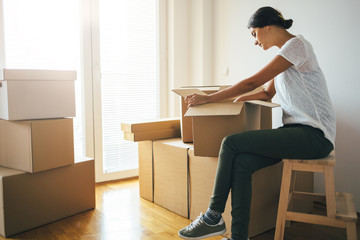 Young woman unpacking moving boxes into new home