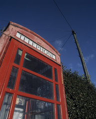 Fototapeta na wymiar Traditional red telephone kiosk with blue sky and telegraph pole