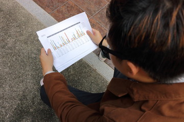 Fototapeta na wymiar Document charts are analyzed by young business worker.