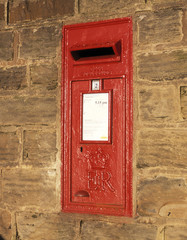 Traditional red Royal Mail post box built into stone wall