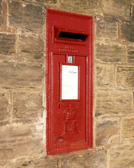 Traditional red Royal Mail post box built into stone wall