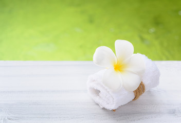 Beautiful Frangipani spa flower with white towel on wood table with nature green pool background