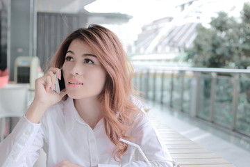 Portrait of attractive young Asian business woman talking on phone for her job in office with copy space background.