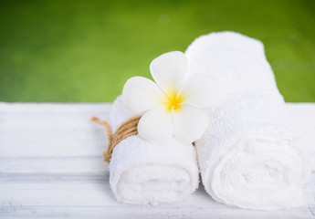 Beautiful Frangipani spa flower with white towel on wood table with nature green pool background