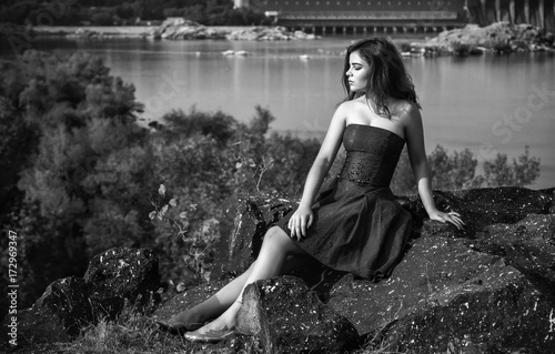 Black And White Portrait Of Beautiful Young Brunette Woman Wearing Elegant Dress Sitting On A