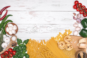 Italian cuisine. Vegetables, oil, spices and pasta on white wooden table background, top view