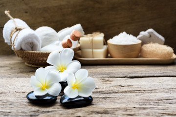 Fototapeta na wymiar Spa wellness concept,white candle,milk soap,salt,towel,flowers and herbal massage ball on white wood table with green pond background