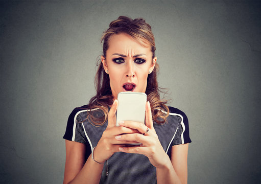 Funny shocked scared woman looking at phone seeing bad news photos message with disgusting emotion on face