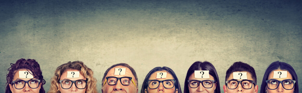 Multiethnic group of thinking people in glasses with question mark looking up