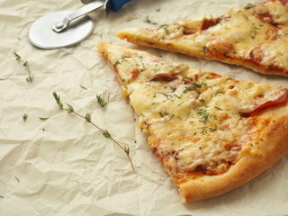 Parchment background with  pepperoni pizza. Homemade pizza with thyme. Copy space for your text. Selective focus.