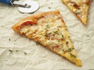 Parchment background with  pepperoni pizza. Homemade pizza with thyme. Copy space for your text. Selective focus.