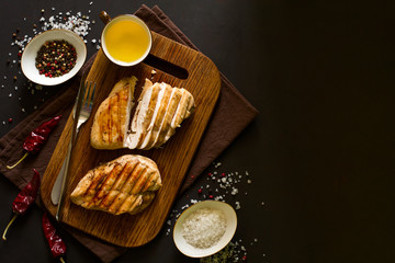 Grilled chicken breasts with spices on wooden desk. Top view. Space for copy. Toned image