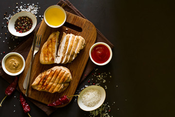 Grilled chicken breasts with spices on wooden desk. Top view. Space for copy. Toned image