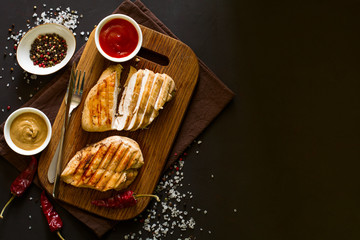Grilled chicken breasts with spices on wooden desk. Top view. Space for copy. Toned image