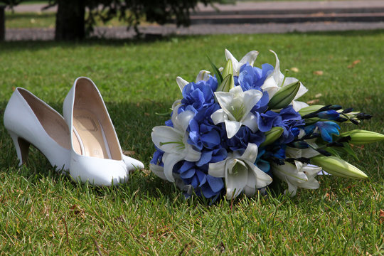 bridal wedding shoes and bouquet on green grass