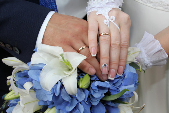 Hands of the bride and groom on a bridal bouquet