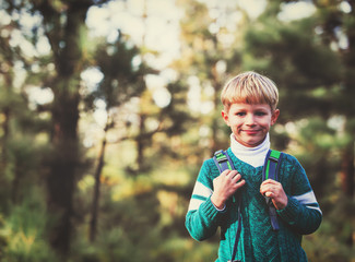 little boy with backpack enjoy travel in green forest