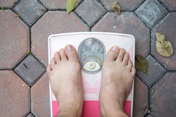 A Male foot on a pink weighing apparatus.