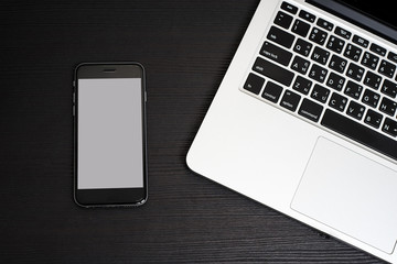 Mobile Phone white background with Laptop Keyboard on Black Wooden Table