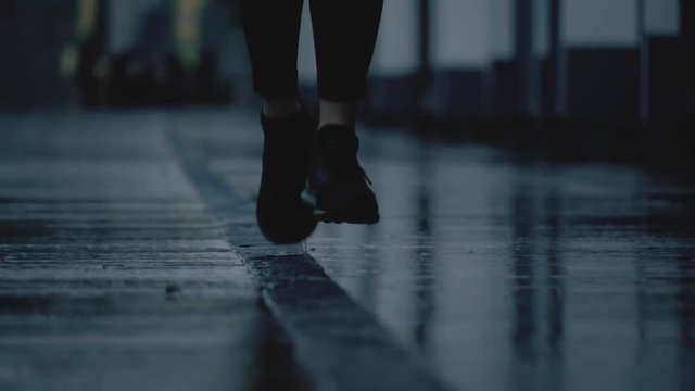 Super slow motion close-up shot of female runner's feet running on wet pavement after rain