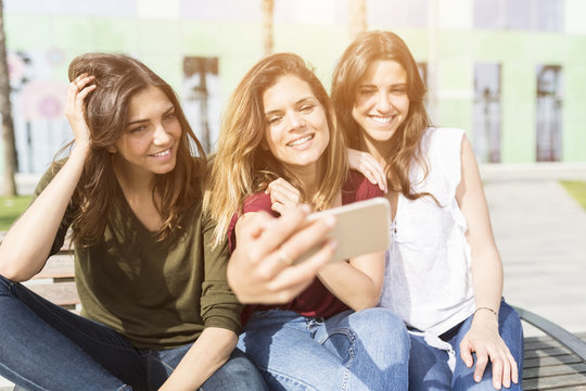Three happy female friends taking a selfie outdoors