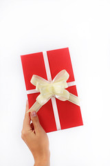 red gift box with bow holds a female hand on a white background