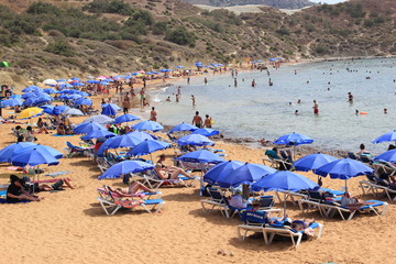 Malta: Touristen, Sonnenschirme und Sonnenliegen am Sandstrand Ghajn Tuffieha