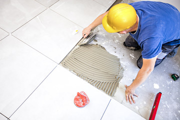 Tile laying tiles at home. Construction worker laid floor tiles.