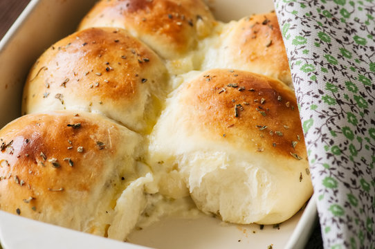 Homemade all-dinner rolls with mozzarella cheese and oregano on a wooden background.