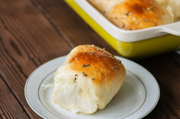 Homemade all-dinner rolls with mozzarella cheese and oregano on a wooden background.
