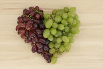 Green and blue grapes lie in the shape of a heart
