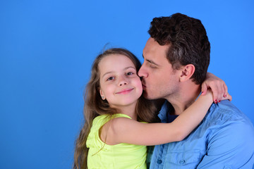 Fototapeta premium Childhood and family concept. Dad kisses his daughter in cheek.