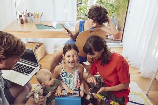 Happy playful family using digital devices in children's room
