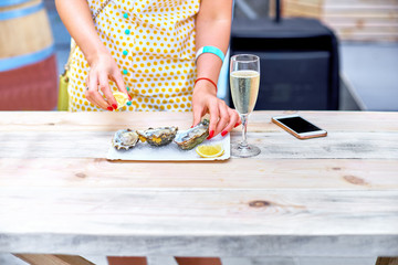 Obraz na płótnie Canvas A woman eats fresh oysters on a plate