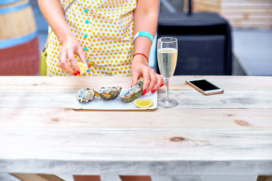 A woman eats fresh oysters on a plate