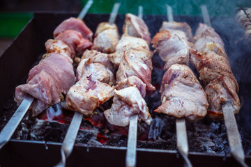 Grilled kebab cooking on metal skewers (grill). Roasted meat cooked at barbecue with smoke. Close up BBQ fresh pork meat chop slices. Traditional eastern dish, shish kebab.