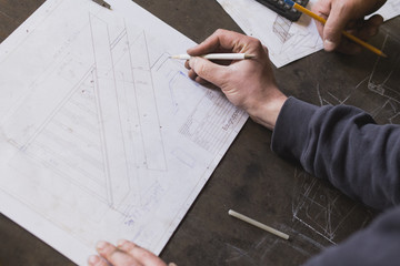 Two blacksmiths are taking measures, do calculations and schedule a days work in a blacksmith's workshop.