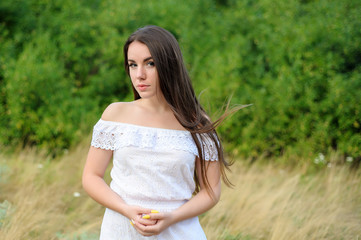 Naklejka na ściany i meble portrait of a young beautiful girl in a park in white dress