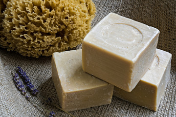 Handmade olive oil soaps, together with a natural sea sponge and a small branch of lavender on sackcloth