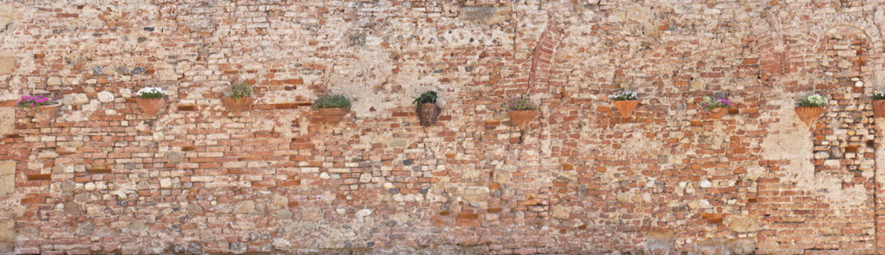 alte Ziegelmauer mit Blumenschmuck in der Toskana © Composer