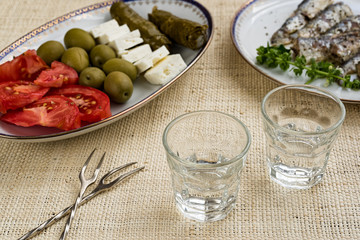 Two glasses of traditional drink Ouzo or Raki and appetizers on natural matting