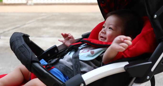 cute boy child laughing happy smile in baby stroller carriage seat