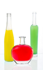 three bottles with alcohol  on a table with the reflecting surface