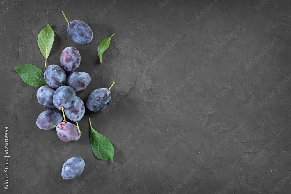 Wall mural Healthy food. Close-up view fresh ripe plum and leaves with copy space