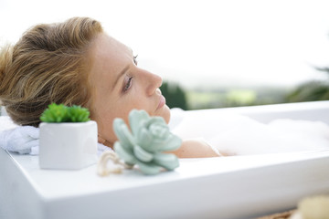 Profile view of woman relaxing in outdoor bathtub